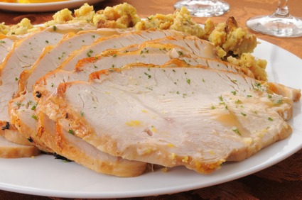 A platter of sliced turkey on top of herbal stuffing