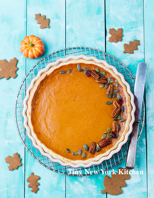 Tasty pumpkin pie, tart made for Thanksgiving day in a baking dish on a cooling rack. Turquoise wooden background