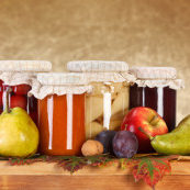 Compotes and jam in glass bottle with fresh fruits on wooden board