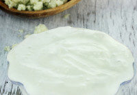 Blue Cheese Salad Dressing 2 Bowl of freshly made blue cheese salad dressing with chunks of blue cheese in wooden spoon on a rustic background.