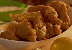 Several pieces of fried catfish filets placed in a plain white boat shaped dish