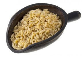 orzo (rosa marina), a rice shaped pasta made of wheat semolina on a rustic wooden scoop isolated on white