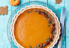 Tasty pumpkin pie, tart made for Thanksgiving day in a baking dish on a cooling rack. Turquoise wooden background