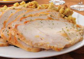 A platter of sliced turkey on top of herbal stuffing