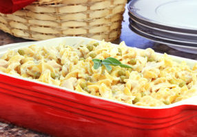 Creamy Tuna and Pasta Dinner with a basket of bread and dinner plates in background. Shallow depth of field.
.
